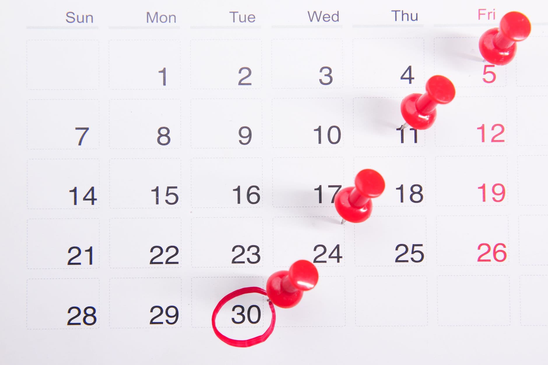 Kalender med røde nåler på flere datoer og en frist ringet inn